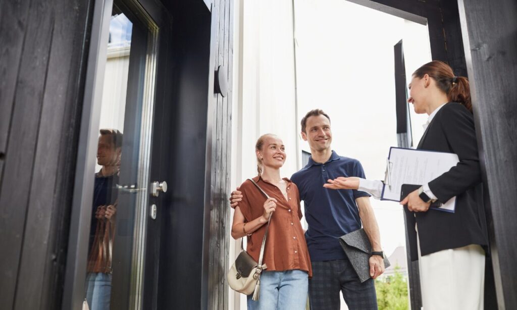 A property agent welcoming a couple at the front door of a home, representing buyers and renters exploring property options while living in Tamworth B79.