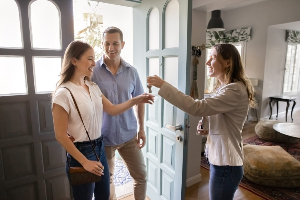 Estate agent handing house keys to a smiling couple at the doorway, reflecting the home selling process and local property market advice for Bradford sellers.