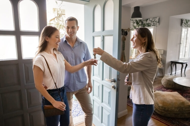 Estate agent handing house keys to a smiling couple at the doorway, reflecting the home selling process and local property market advice for Bradford sellers.
