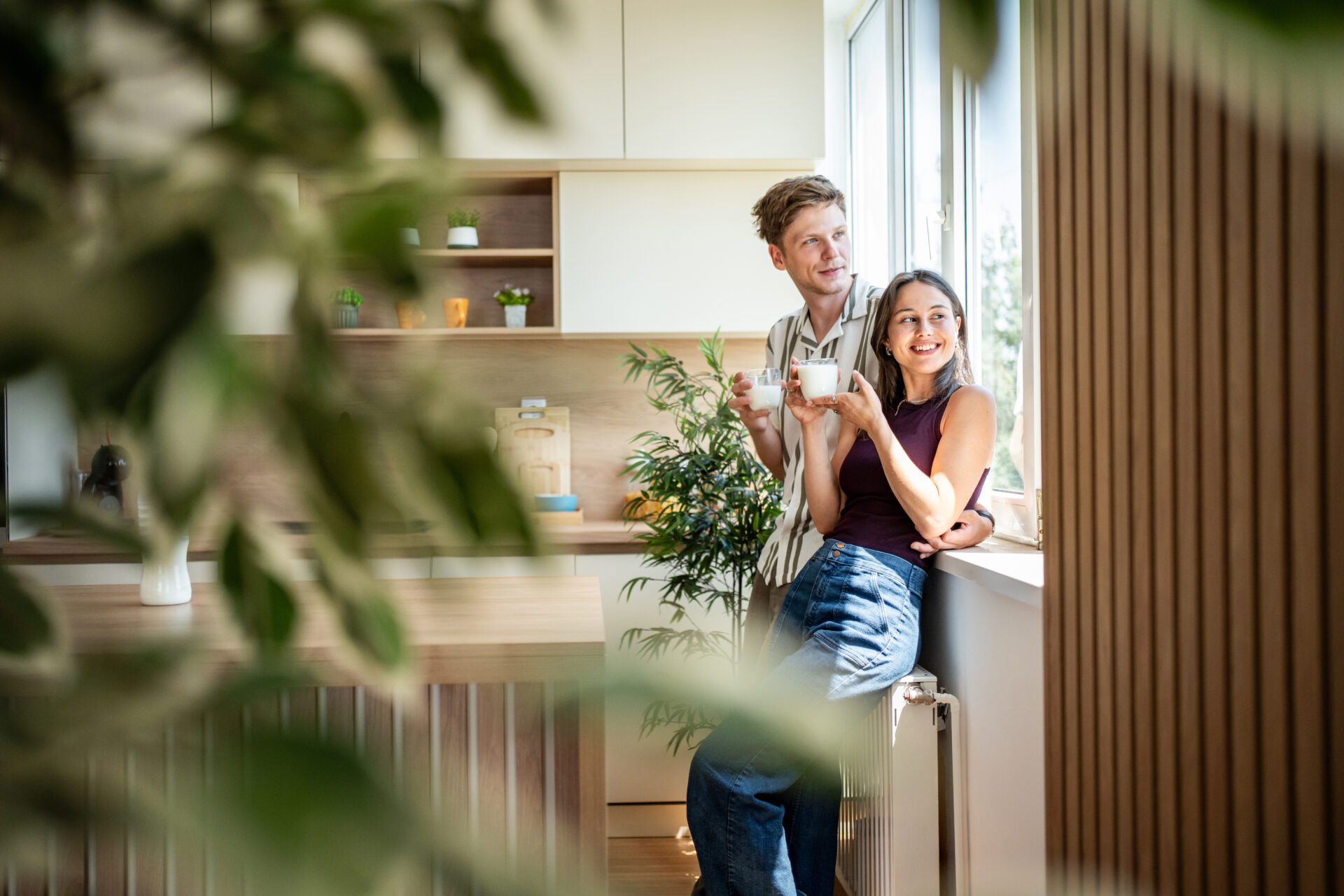 Couple relaxing with drinks in a bright modern kitchen, reflecting the lifestyle appeal of buying a home in Lichfield.