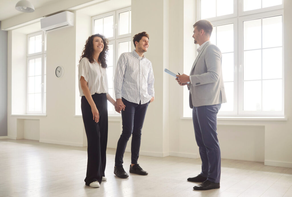 Estate agent showing a smiling couple around a bright empty property, reflecting the home-buying process and buyer advice for Camberwell in 2026.
