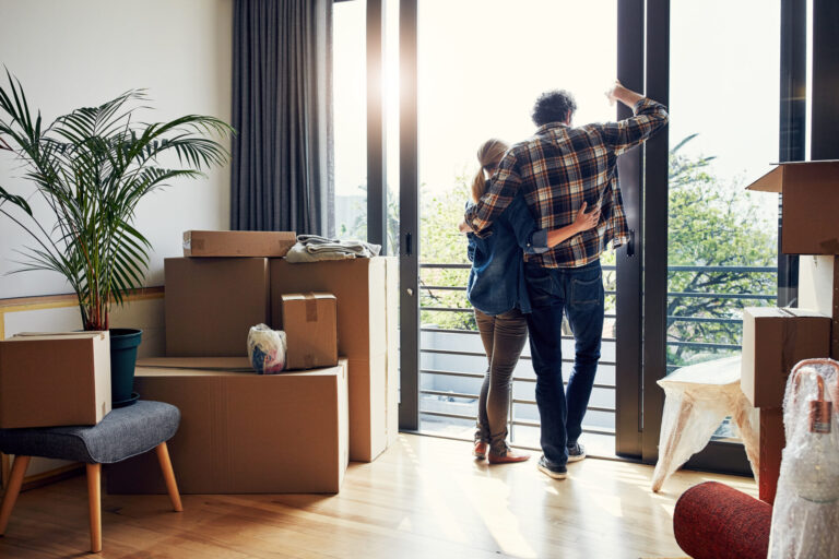 Couple standing in their new home surrounded by moving boxes, reflecting the experience of buying a property and moving to Chesterfield.