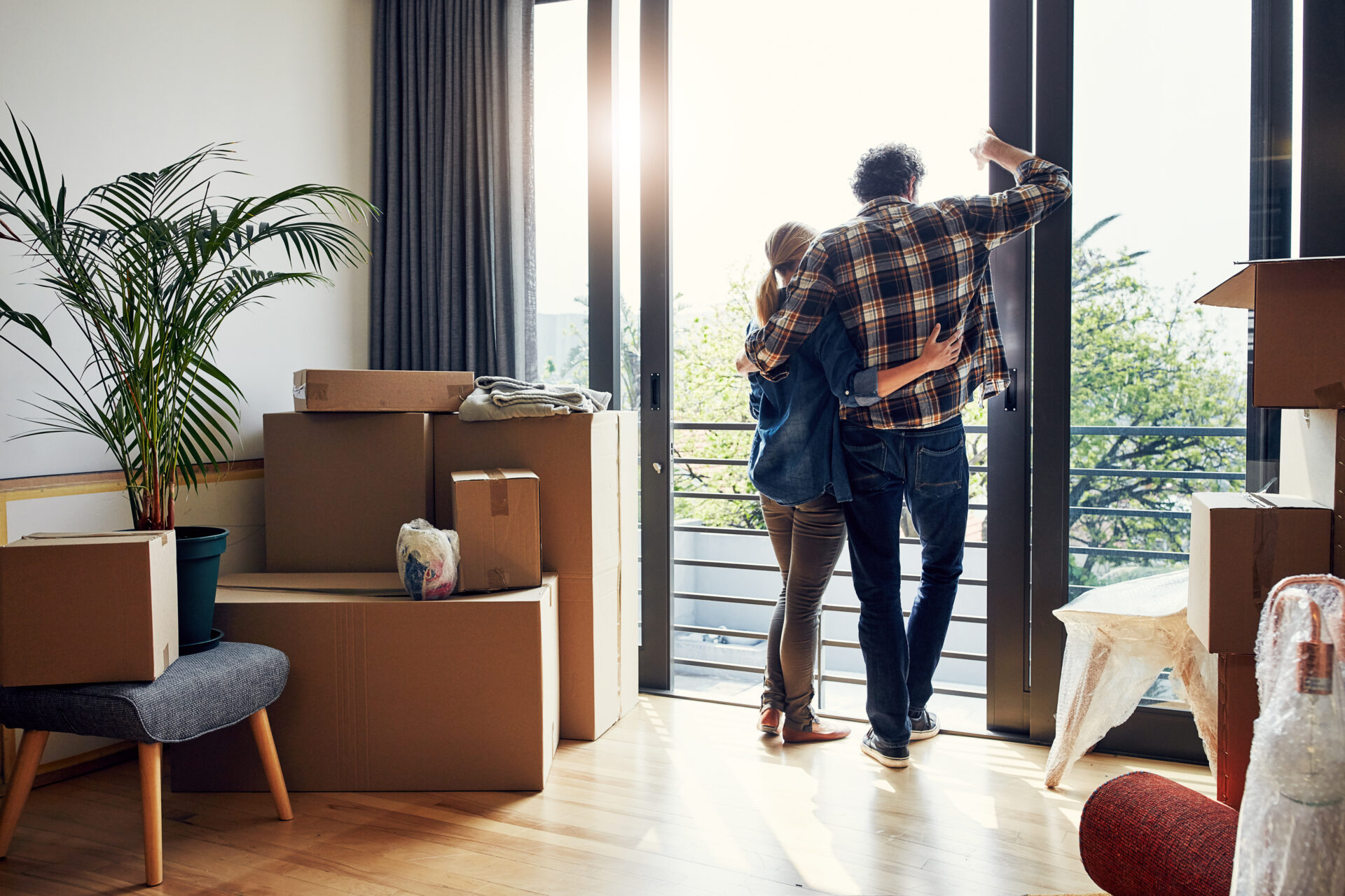 Couple standing in their new home surrounded by moving boxes, reflecting the experience of buying a property and moving to Chesterfield.