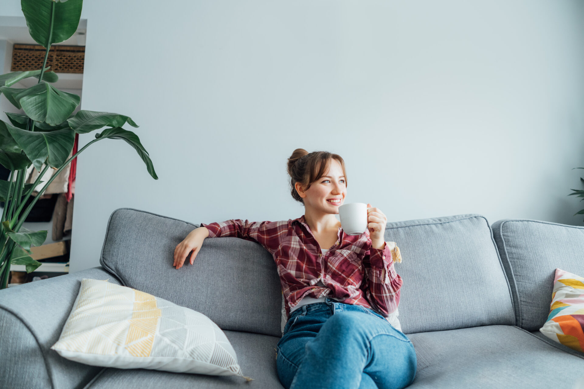 Woman relaxing on a sofa in a bright modern home, reflecting comfortable living and the importance of understanding property values in Harborne.