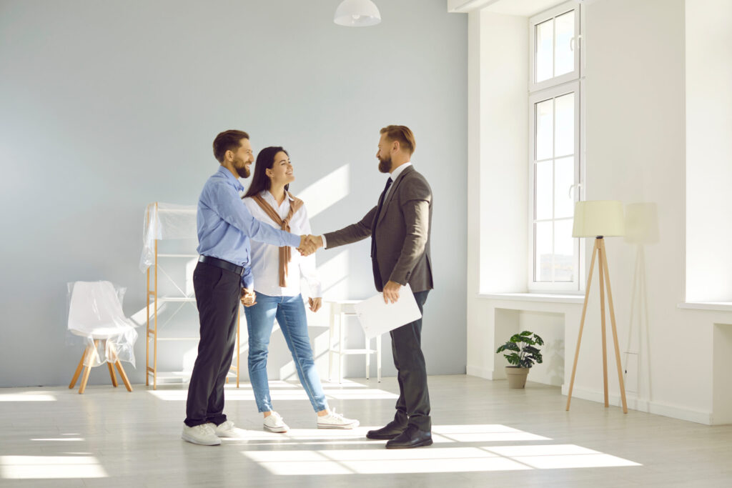 Estate agent shaking hands with a couple inside a bright property, reflecting the home selling process and local property market advice for Harrogate sellers.