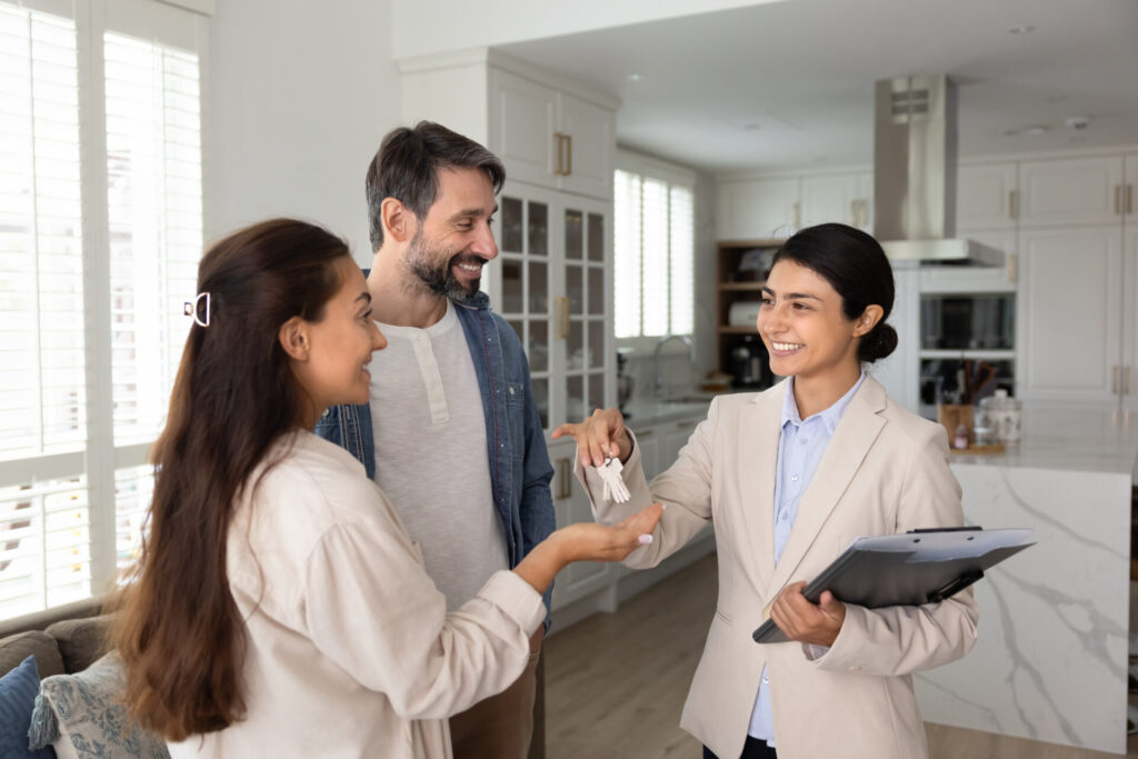 Estate agent handing keys to a couple inside a modern home, reflecting the process of renting a property in Southampton.