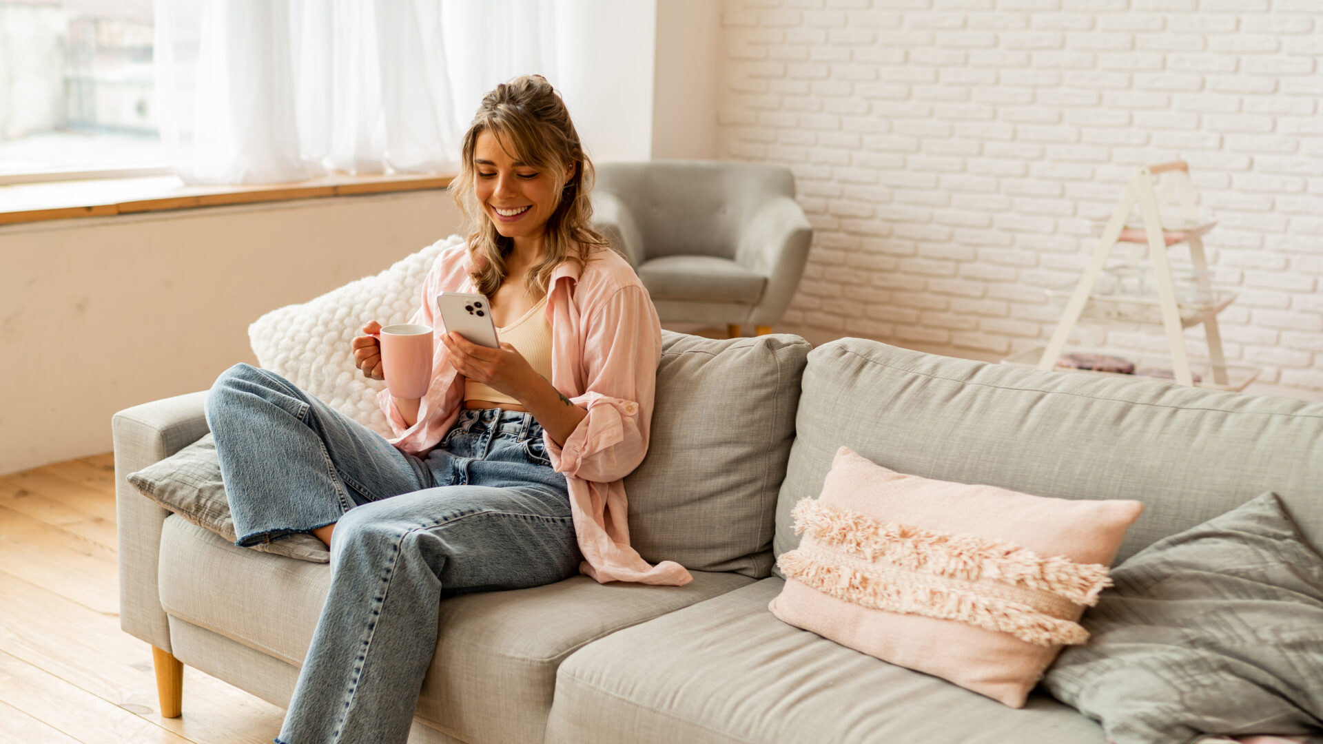 Woman relaxing at home while using her phone, representing homeowners planning to upsize and sell their property in Annan.