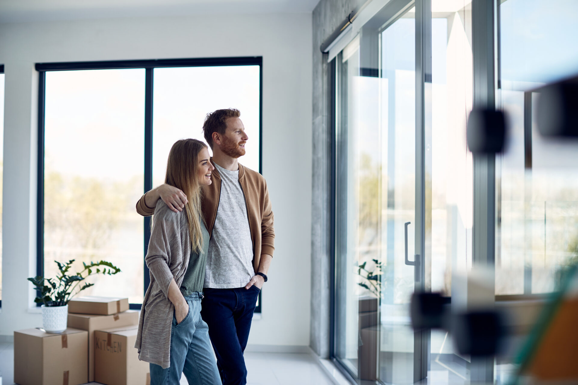 Couple standing in a bright modern home with moving boxes, reflecting the lifestyle appeal and buyer demand for homes in Stanmore.