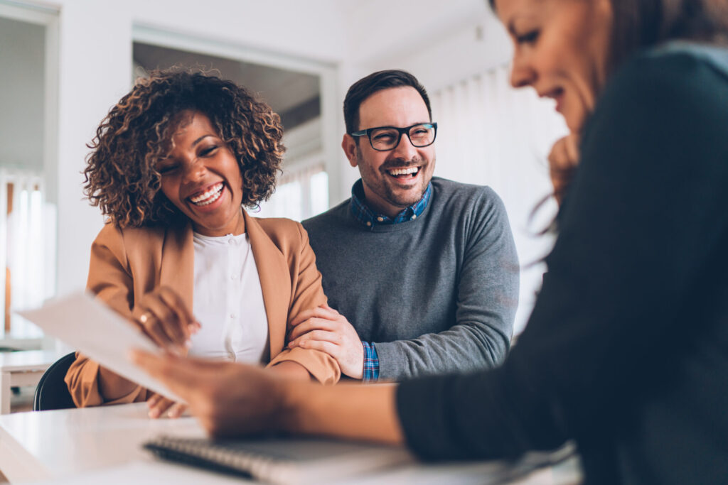 Couple smiling while discussing property documents with an estate agent, reflecting advice and support for buying or selling in Solihull and Birmingham.