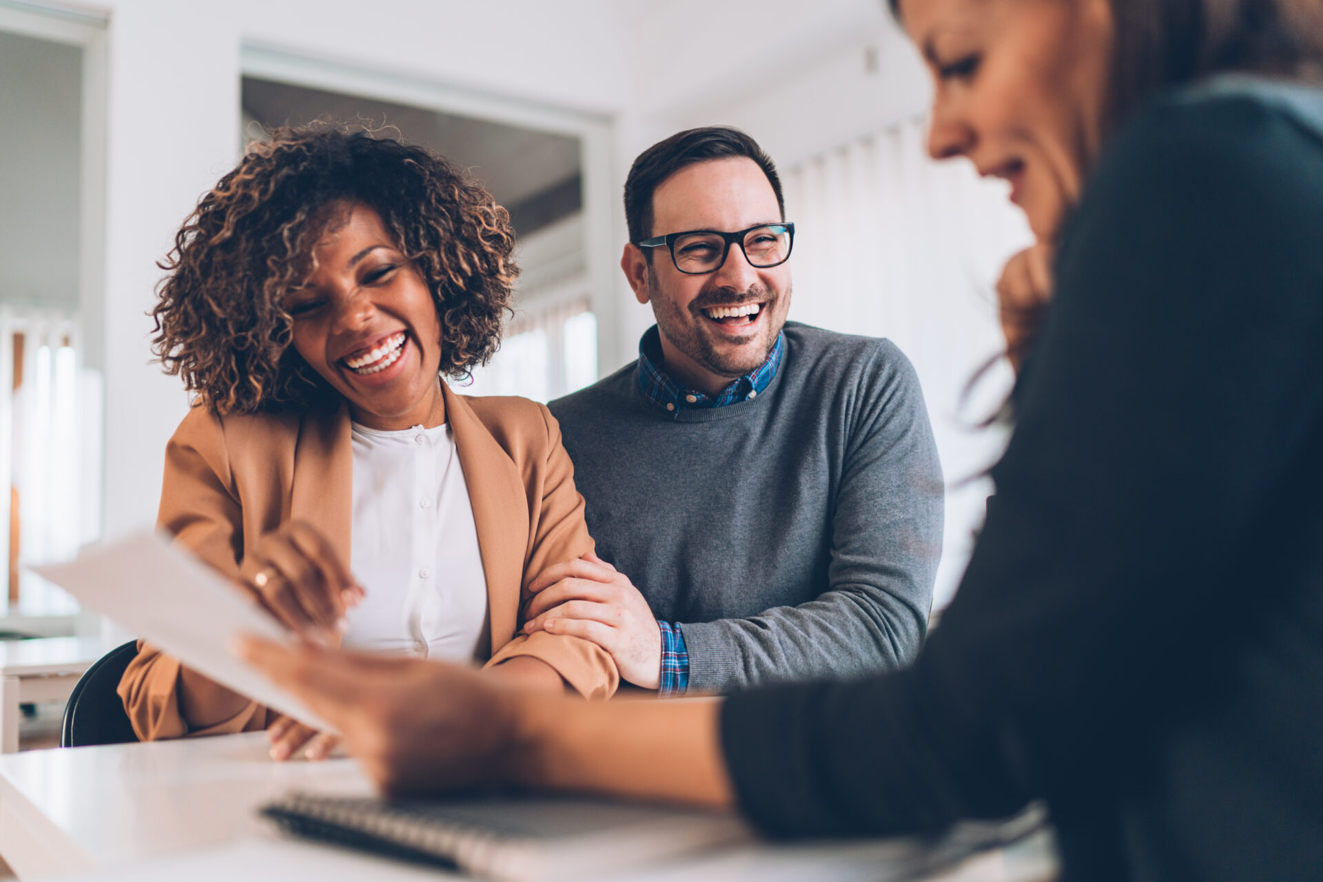 Couple smiling while discussing property documents with an estate agent, reflecting advice and support for buying or selling in Solihull and Birmingham.