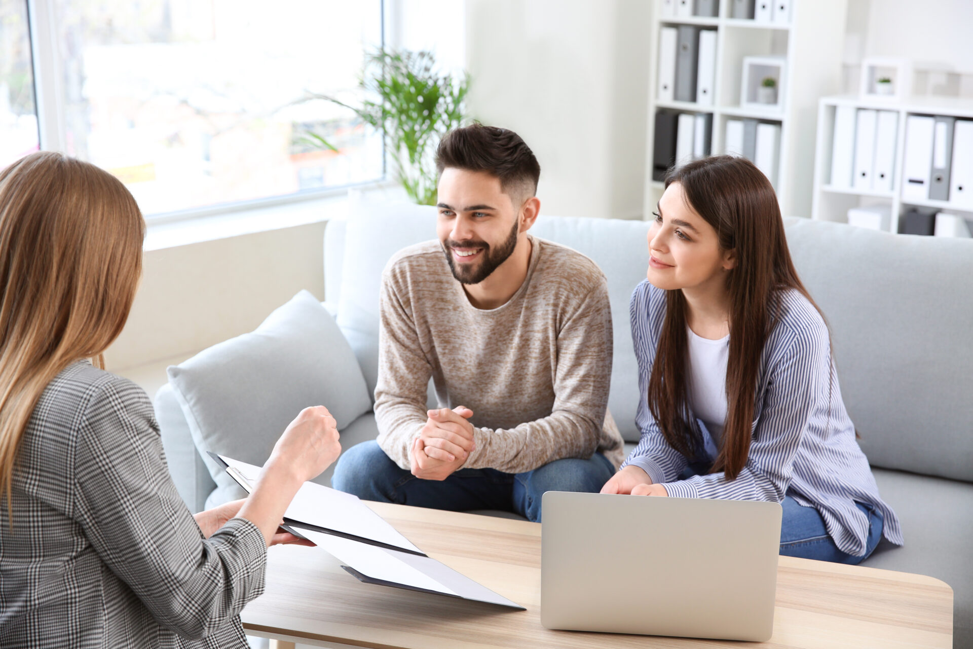 Couple discussing property details with an estate agent in a bright office, reflecting home valuation advice and market guidance for Stourbridge sellers.