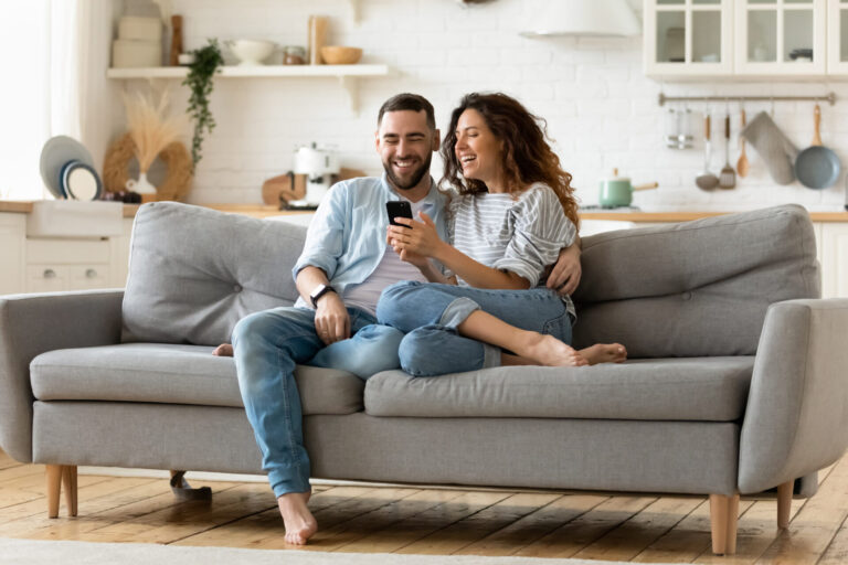 Couple relaxing at home while looking at a phone, representing buyers considering a move to Dumfries.