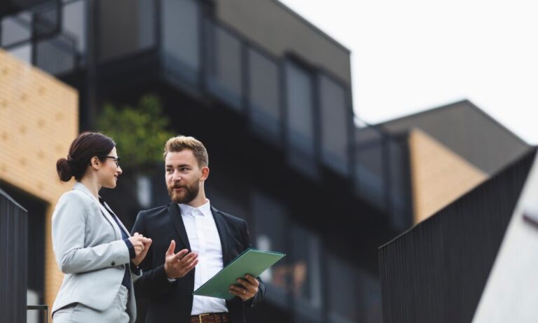 Estate agents standing outside a modern property, discussing the York housing market and home-buying process.