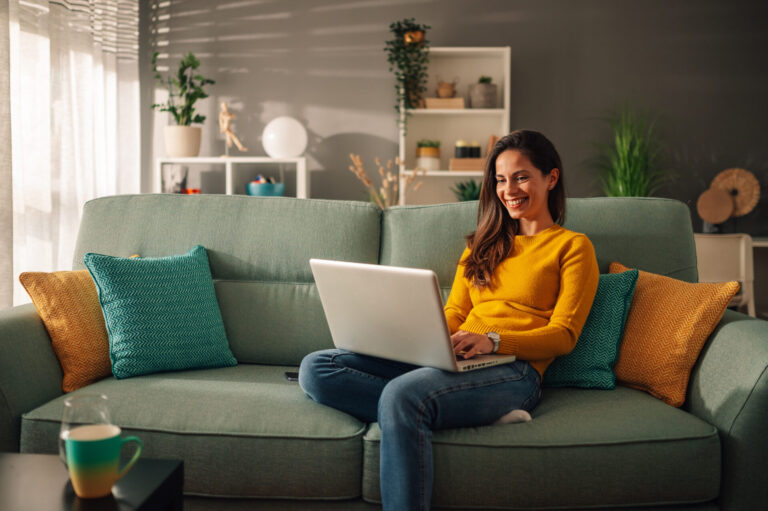 Woman using a laptop while relaxing in a modern living room, representing the comfortable lifestyle and residential appeal of Clifton YO30.