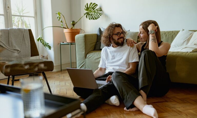 Couple relaxing together at home while looking at a laptop, representing the welcoming lifestyle and residential appeal of Hall Green B28.