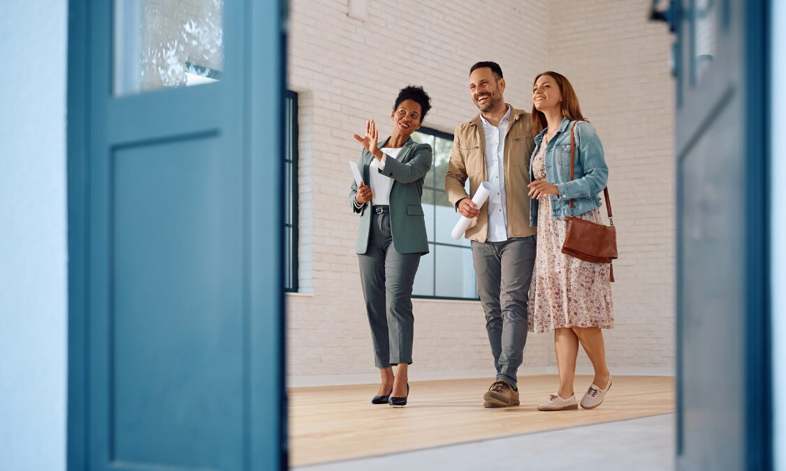 Estate agent showing a modern property to a couple, representing buying and living in Oxenholme, Kendal.
