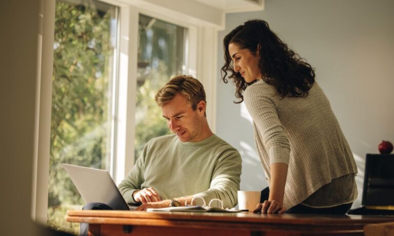 Couple looking at a laptop together in a bright modern home, representing the rental lifestyle and residential appeal of Headingley, Leeds.
