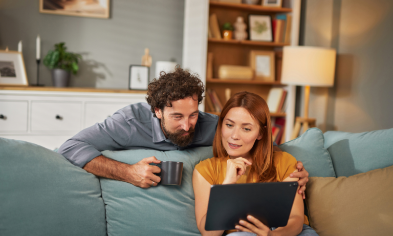 Couple using a tablet at home while researching selling their property in Carlisle.