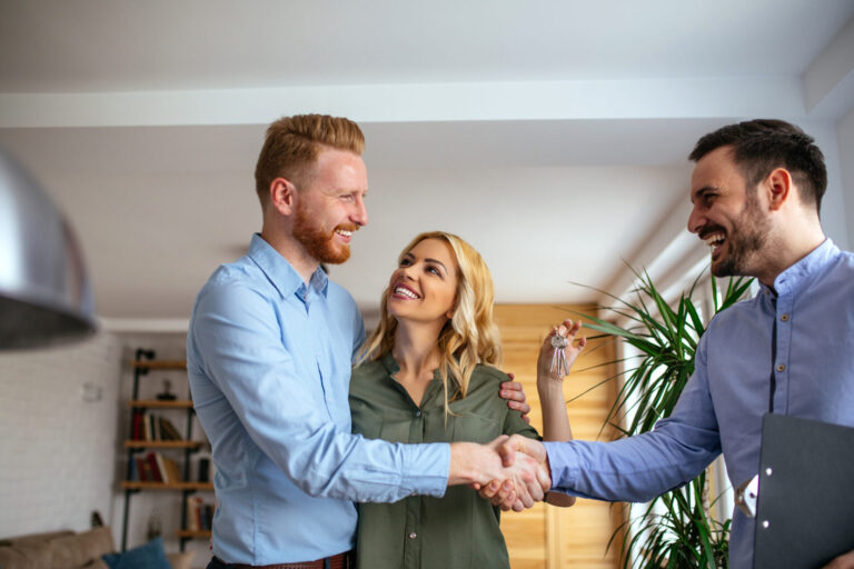 Landlord and tenant shaking hands with a letting agent after receiving the keys to a rental property.