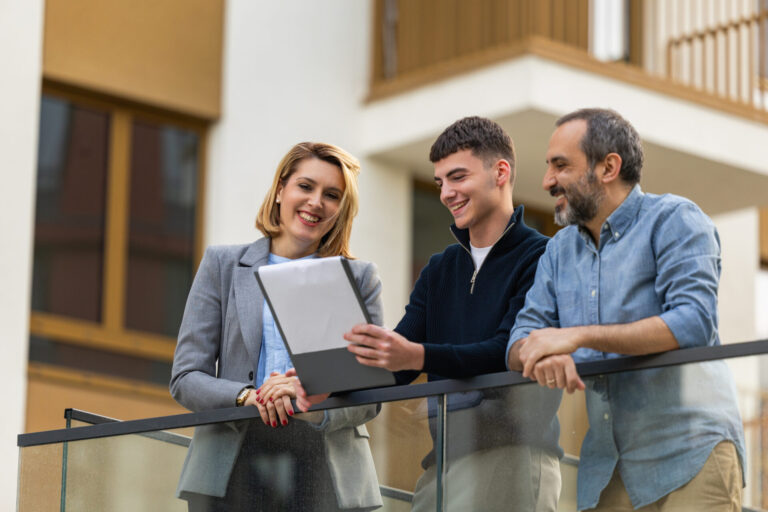 Property agent reviewing documents with two clients on a balcony