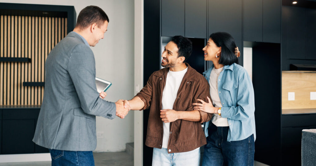 Property agent shaking hands with a couple inside a modern kitchen