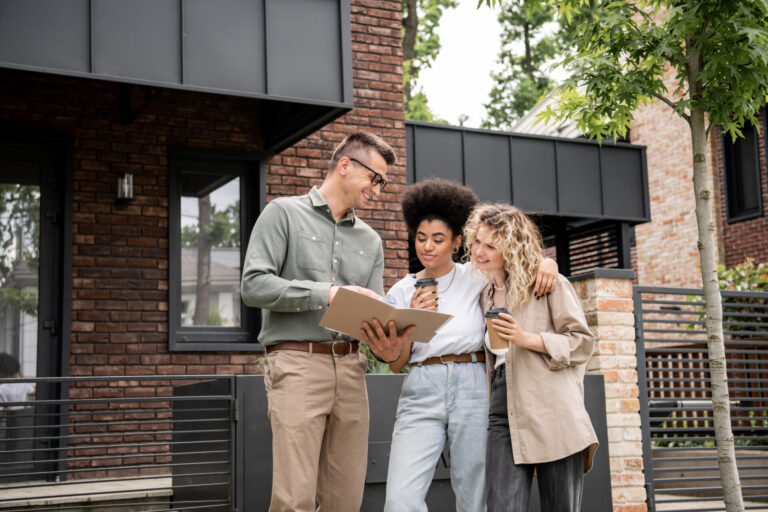 Property agent reviewing paperwork with two clients outside a modern home