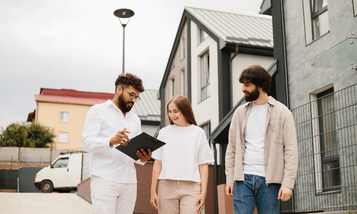 Letting agent discussing property management with tenants outside a modern rental property.