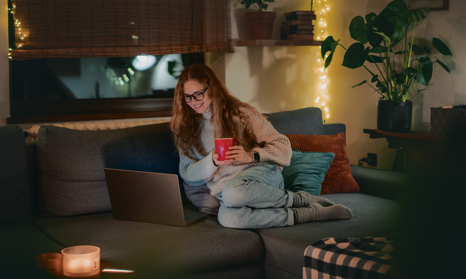 Young woman relaxing on a sofa researching properties on a laptop in the evening, reflecting a first-time buyer learning about LBTT and Home Reports in Dumfries.
