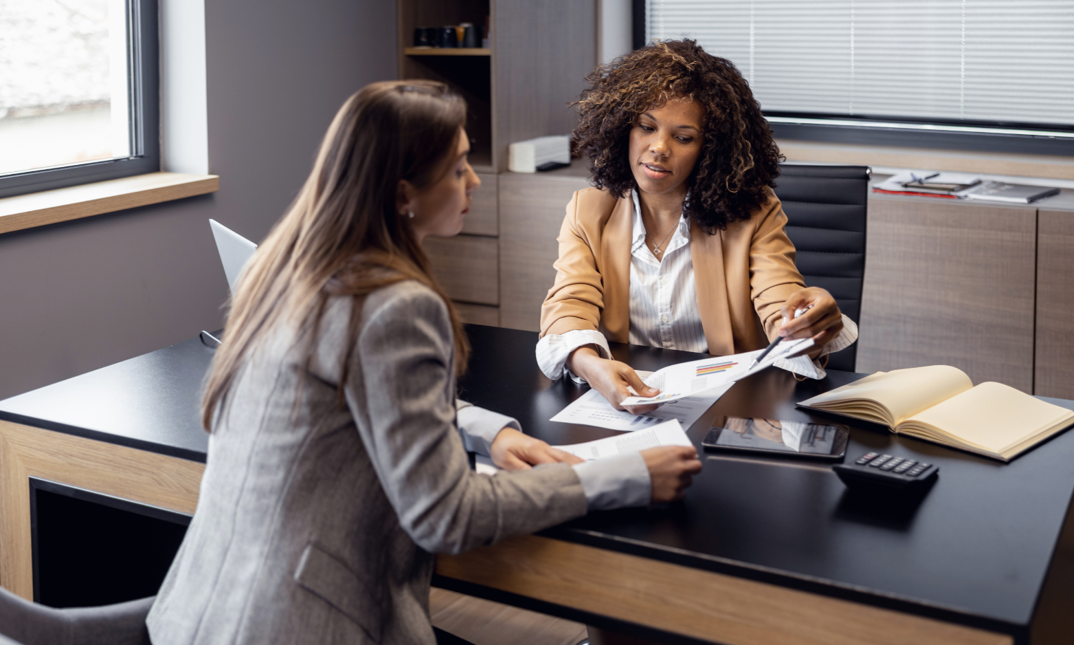 Two property professionals reviewing figures and paperwork with a calculator at an office desk, reflecting the evidence-based pricing strategy the article recommends.