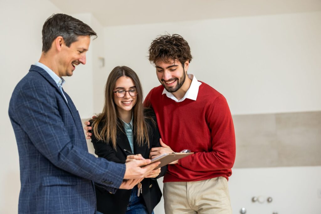 Estate agent showing a tablet to a smiling young couple during a property viewing in Kingstanding B44