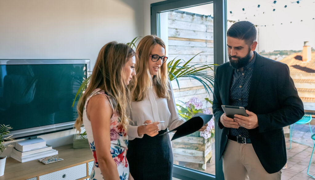 Three people reviewing property documents and a tablet during a professional consultation inside a modern residential property.