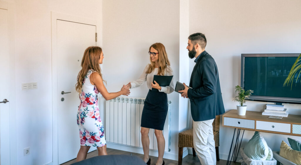 Estate agent shaking hands with a homeowner during a property consultation in a bright, modern living room.
